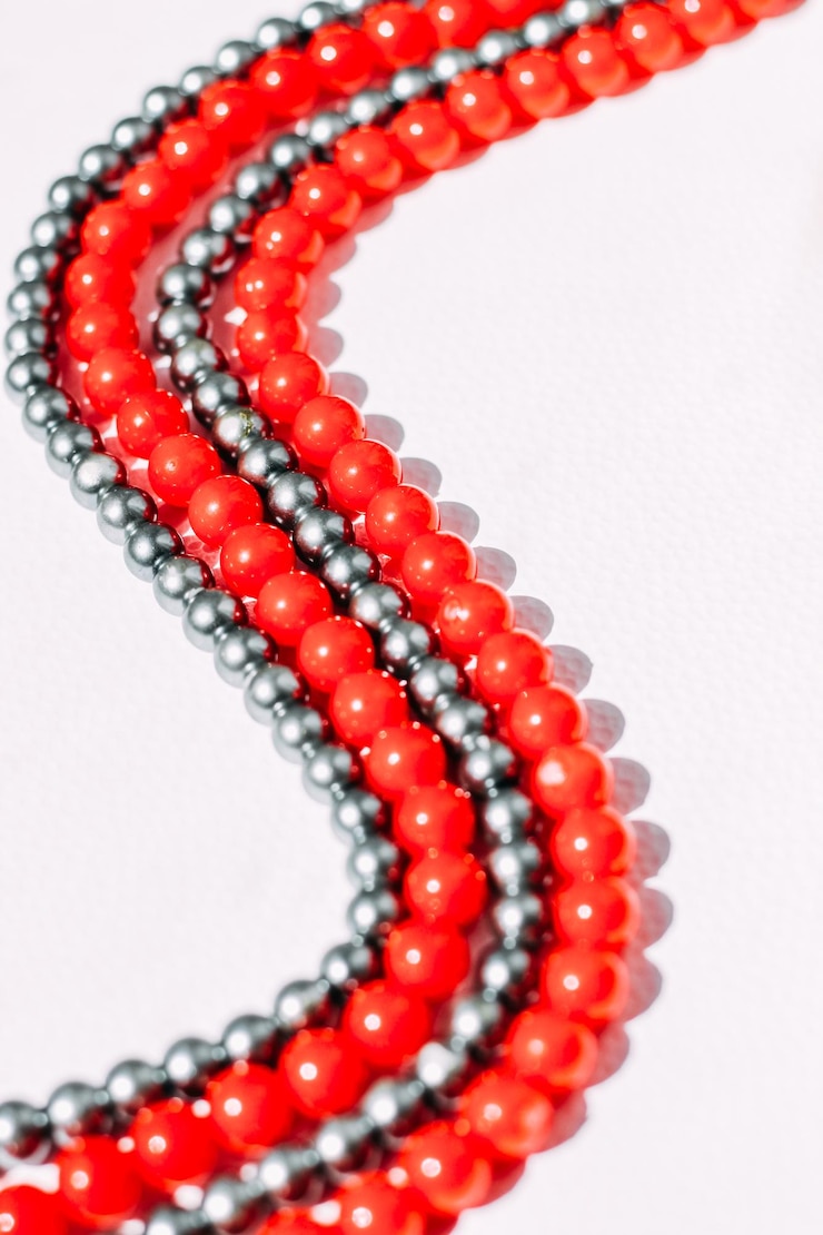 Foto un collar de cuentas rojas y grises sobre un fondo estético blanco