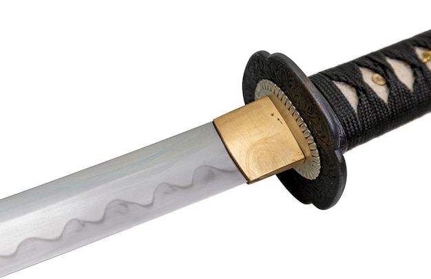 El collar Habaki está hecho de latón pulido Está en la base de una hoja de espada japonesa con un patrón ondulado en la parte afilada aislado en un fondo blanco Enfoque selectivo