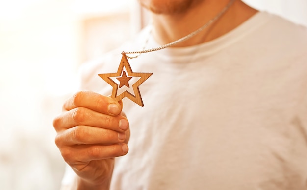 El collar de madera con forma de estrella en la mano del hombre.