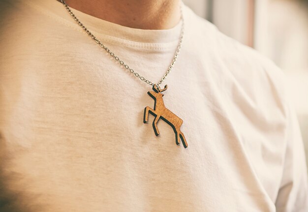 El collar navideño de madera con forma de ciervo en el cuello del hombre con una camiseta blanca