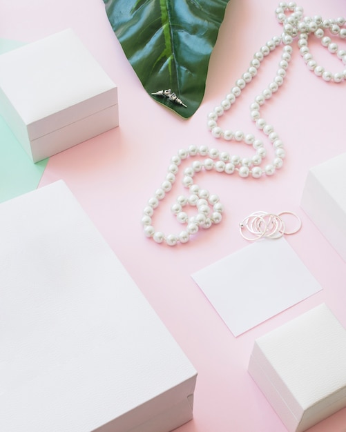 Foto collar de perlas y pendientes con cajas blancas sobre fondo rosa