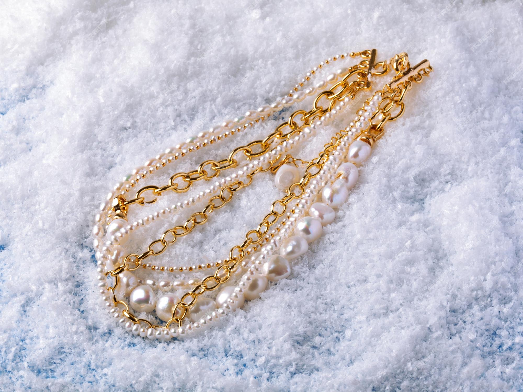 Collares de oro y perlas barrocas elegantes lujo fondo de nieve blanca. fotografía de cerca | Foto Premium