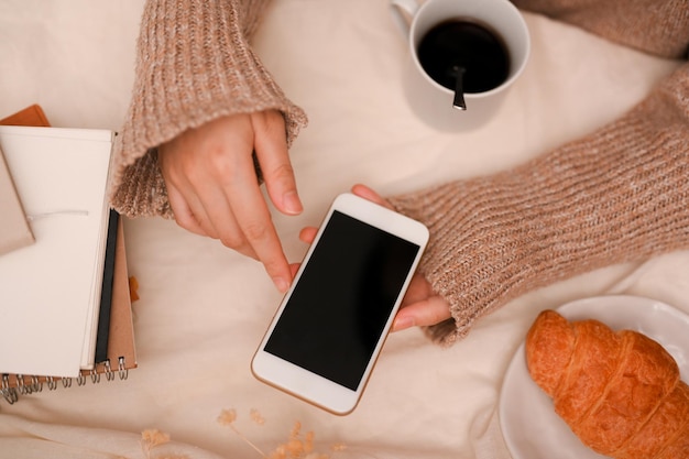 College-Frau arbeitet im Café fern und sucht mit dem Smartphone nach etwas im Internet