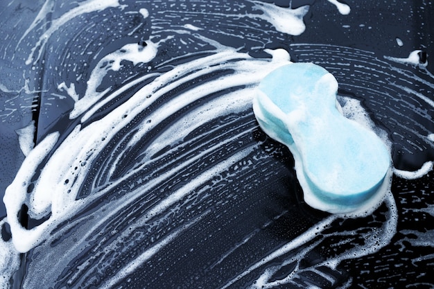 Se coloca una esponja azul para lavar el automóvil en un automóvil negro.