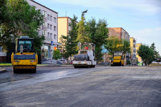 Colocación de asfalto nuevo con pistas de hieloEl equipo de construcción de carreteras está funcionandoReparar carretera vieja
