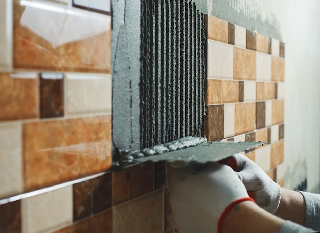 Colocación de baldosas cerámicas. Tiler ofrece adhesivo para azulejos en la pared