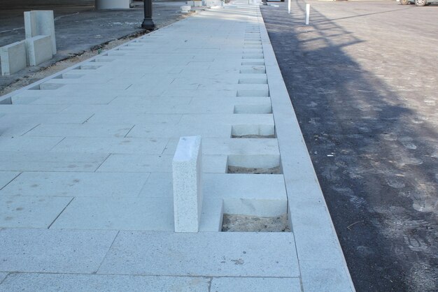 Colocación de ladrillos al aire libre, losas de pavimento gris de hormigón en la calle. Desarrollo de infraestructura urbana con