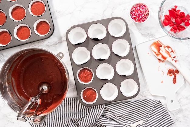 Colocación plana Colocación plana Sacar la masa para cupcakes en un molde para cupcakes para hornear cupcakes de terciopelo rojo