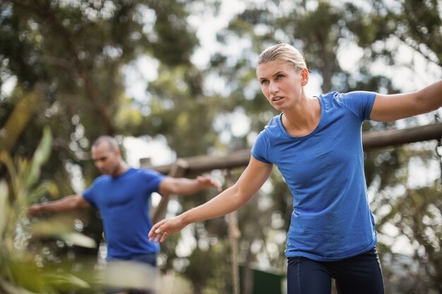 Colocar al hombre y a la mujer durante el entrenamiento de la carrera de obstáculos en el campo de entrenamiento