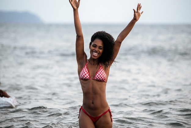 Colocar hermosa mujer negra juguetona en bikini en una playa volcánica en Santo Antao, Cabo Verde