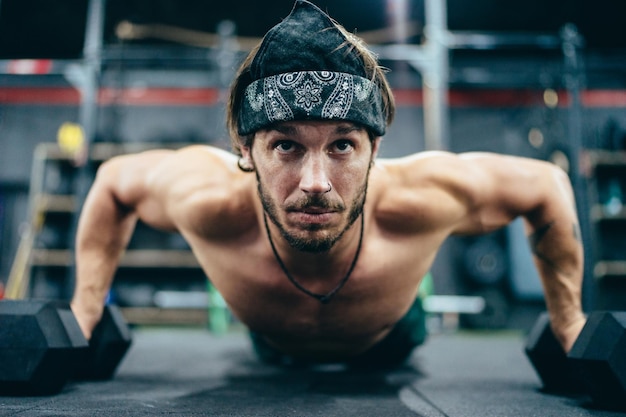 Colocar hombre haciendo flexiones con pesas en un gimnasio