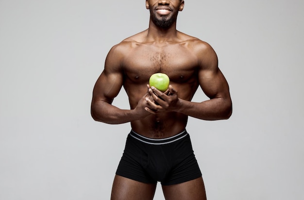 Colocar joven con hermoso torso con manzana verde aislado sobre fondo gris