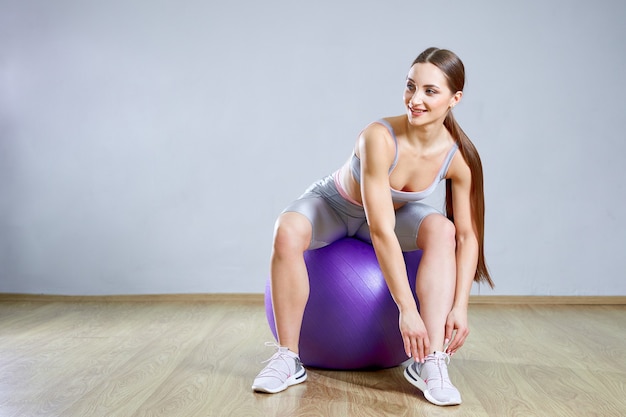 Colocar joven mujer haciendo ejercicio en un gimnasio. Chica de deportes está entrenando fitness cruzado con bolas de Pilates.