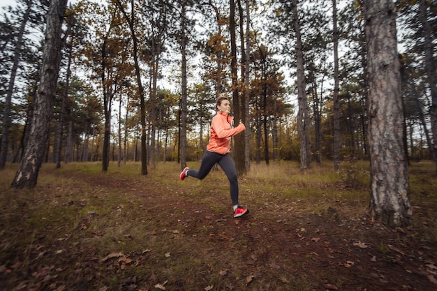 Colocar joven mujer en ropa deportiva corre a lo largo de camino forestal