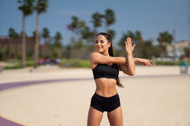 Colocar joven mujer en ropa deportiva haciendo estiramiento del brazo