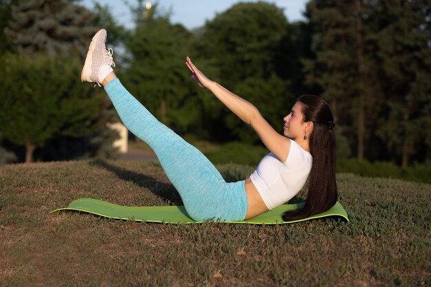 Colocar joven mujer vistiendo ropa deportiva haciendo ejercicios de estiramiento en el parque al atardecer