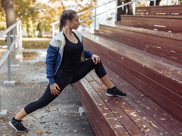 Foto colocar mujer delgada está practicando estiramiento de piernas. entrenamiento al aire libre. concepto de estilo de vida saludable