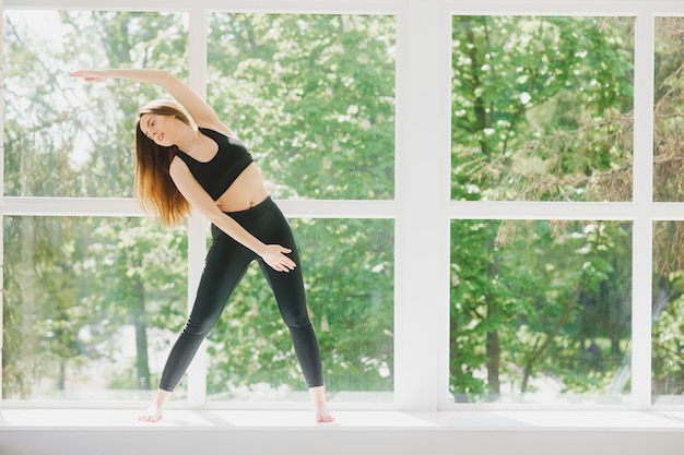 Colocar mujer pose yoga ejercicio en estudio sobre ventana panorámica