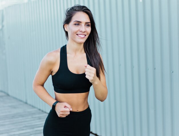 Colocar mujer en ropa deportiva corriendo al aire libre en el entorno urbano.