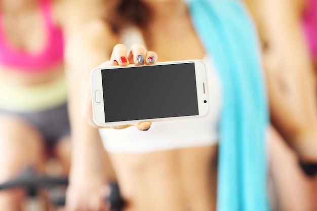 Colocar mujer sosteniendo smartphone en gimnasio