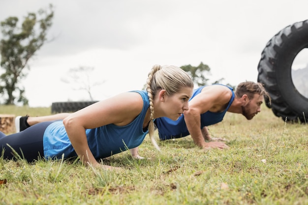 Colocar personas que realizan ejercicio de flexiones en el campo de entrenamiento