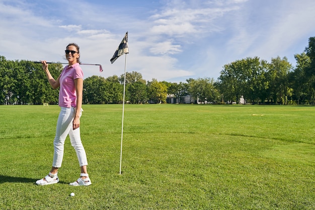 Colocar sonriente joven con un putter posando para la cámara