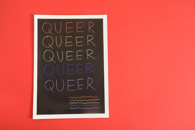 Coloful Inschrift queer auf schwarzem Brett auf rotem Hintergrund