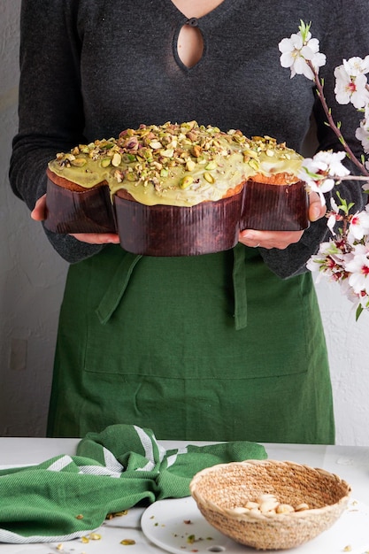 Colomba di Pasqua in der Frau Shef übergibt traditionellen italienischen Ostern-Taubenkuchen mit grüner Pistazienglasur frische Frühlingsblumen Pasqua-Kuchen