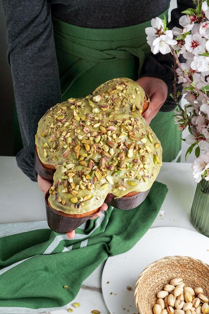 Colomba di Pasqua na mulher shef entrega o tradicional bolo italiano de páscoa pomba com esmalte verde pistache flores frescas da primavera bolo pasqua