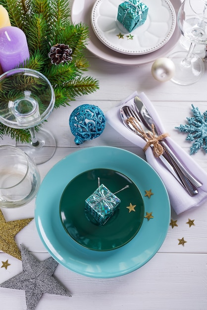 Coloque a configuração da tabela para a mesa branca de Natal com elementos de decoração roxa com galhos verdes