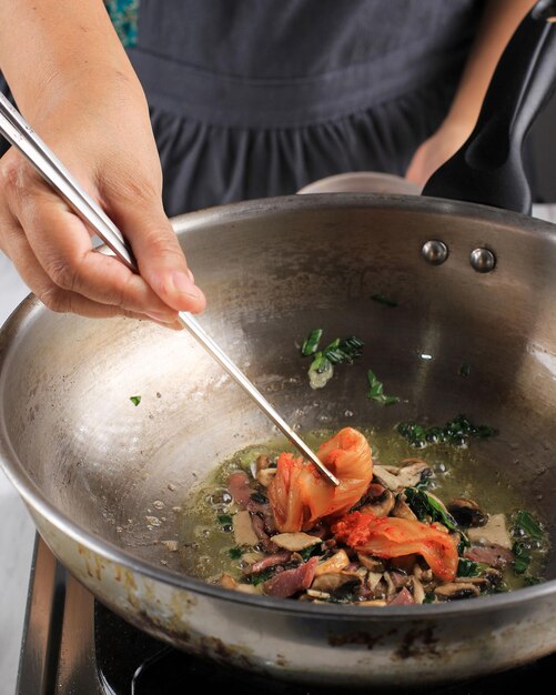 Coloque Kimchi com pauzinho no processo de cozimento na panela Fazendo comida coreana Kimchi Bokkeumbap Foco seletivo