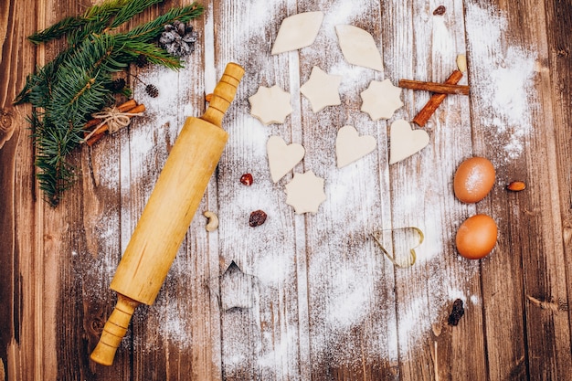 Coloque en la mesa de madera con rodillo, masa, huevos y harina para cocinar pasteles de Navidad