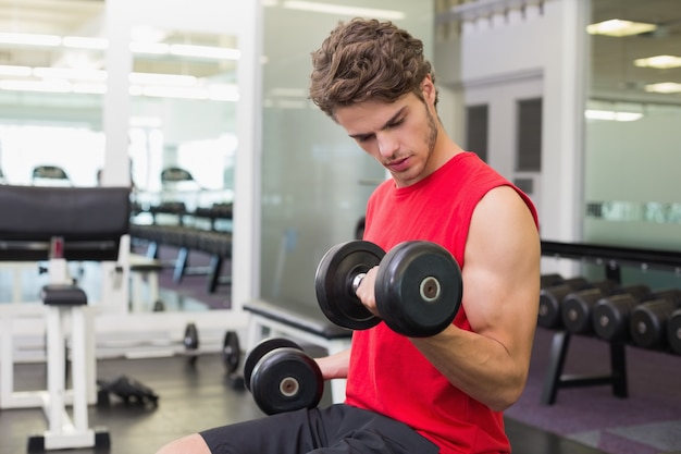 Coloque o homem levantando pesados ​​dumbbells negros