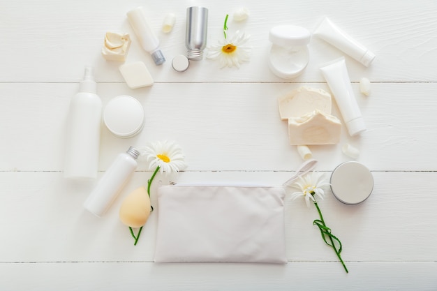 Coloque los productos naturales para el cuidado de la piel de baño en envases blancos sobre la mesa de madera. Cosméticos de spa para la salud de la belleza en el hogar. Neceser, neceser, flores, jabón, crema hidratante. Espacio de copia de marco de maqueta.