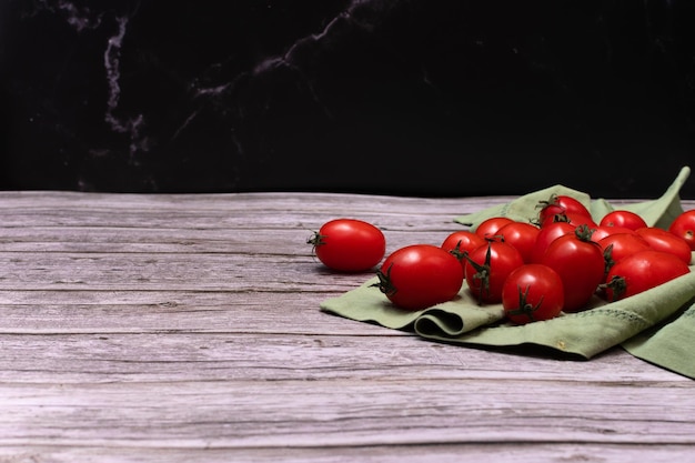 Coloque tomates cherry sueltos sobre la mesa con un paño verde