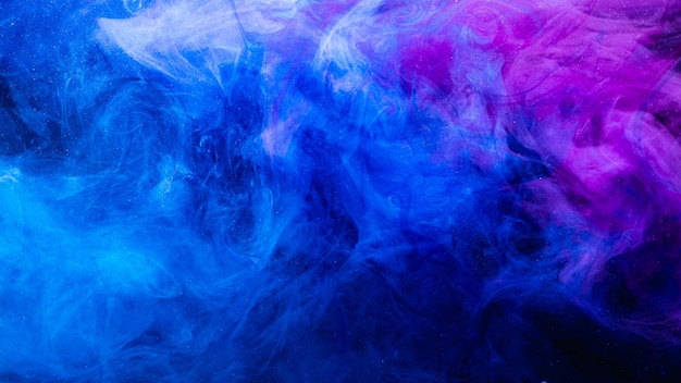 Color en agua. Fondo de arte. Textura de vapor brillante fluorescente. Mezcla de nubes de humo de purpurina púrpura azul ultravioleta brillante en la oscuridad.