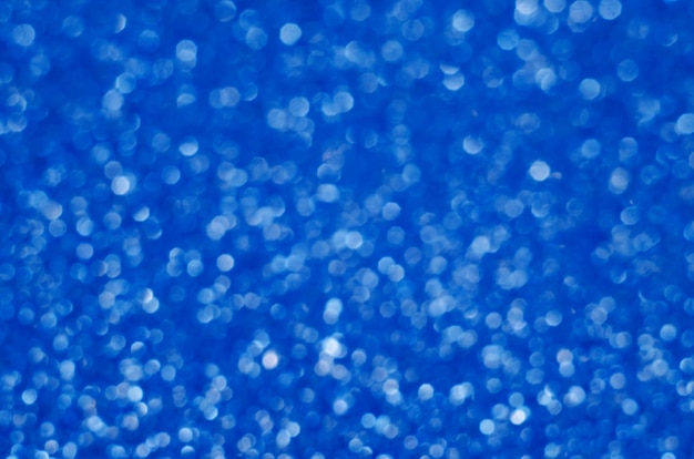 Foto color azul clásico. color del año 2020. fondo abstracto festivo bokeh con destellos brillantes desenfoque. macro de polvo brillante de brillos borrosos de cerca, copie el espacio para el logotipo de texto
