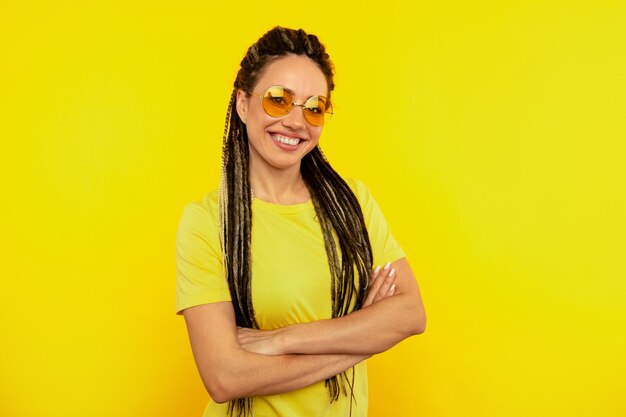 Color fresco. Mujer feliz con largas rastas posando sobre fondo amarillo.