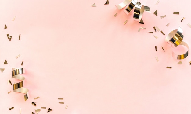 Color plateado de cinta rodante y confeti sobre fondo rosa con espacio de copia
