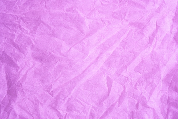 Foto el color rosado arrugó la textura del fondo del tejido de papel.