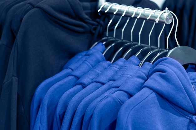 El color tendencia del año 2020 Classic Blue. Sudaderas con capucha en perchas en una tienda de ropa, de cerca.