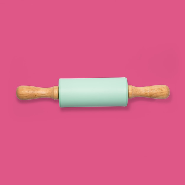 Foto color verde de madera del rodillo en fondo rosado. concepto minimalista