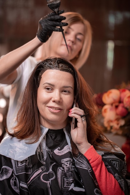 Coloração de cabelo no salão de cabeleireiro O assistente profissional pinta o cabelo no salão Conceito de beleza cuidados com os cabelos