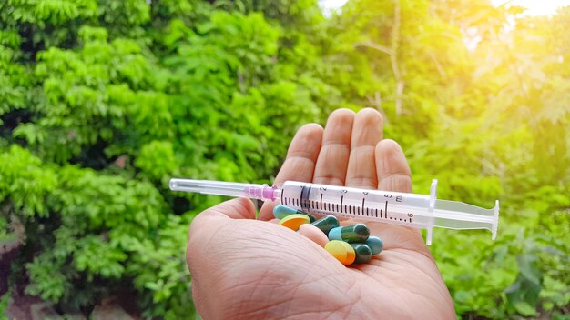 Foto los colores de las pastillas de medicina y la jeringa de plástico están en la palma de la mano