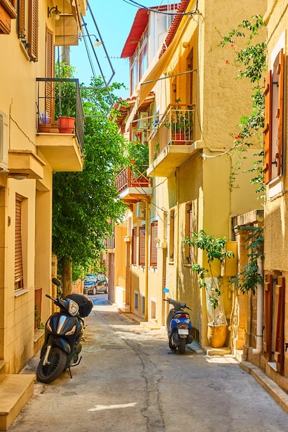 Colorida y acogedora calle griega con motos aparcadas en un día soleado de verano en la ciudad de Aegina, la isla de Aegina, Grecia