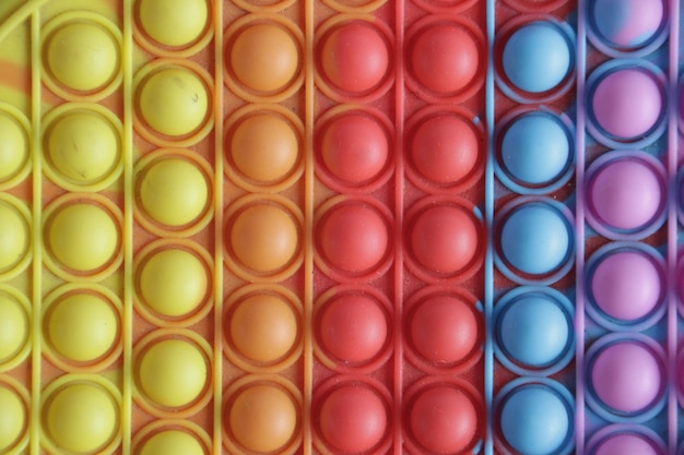 Una colorida bandeja de bolas de plástico de diferentes colores está alineada en filas.