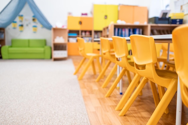 Foto colorida clase de jardín de infantes sin silla de escritorio de educación escolar para niños juguete y decoración en la pared de fondo infancia