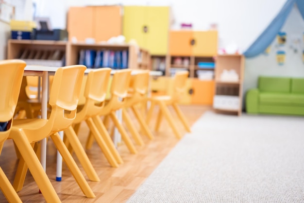 Foto colorida clase de jardín de infantes sin silla de escritorio de educación escolar para niños juguete y decoración en la pared de fondo infancia