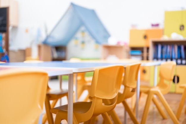 Foto colorida clase de jardín de infantes sin silla de escritorio de educación escolar para niños juguete y decoración en la pared de fondo infancia