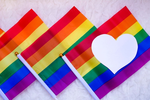 Foto coloridas banderas del orgullo gay con un corazón blanco a la izquierda.